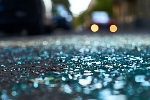 Sharp shards of car glass on the asphalt from a hit-and-run accident